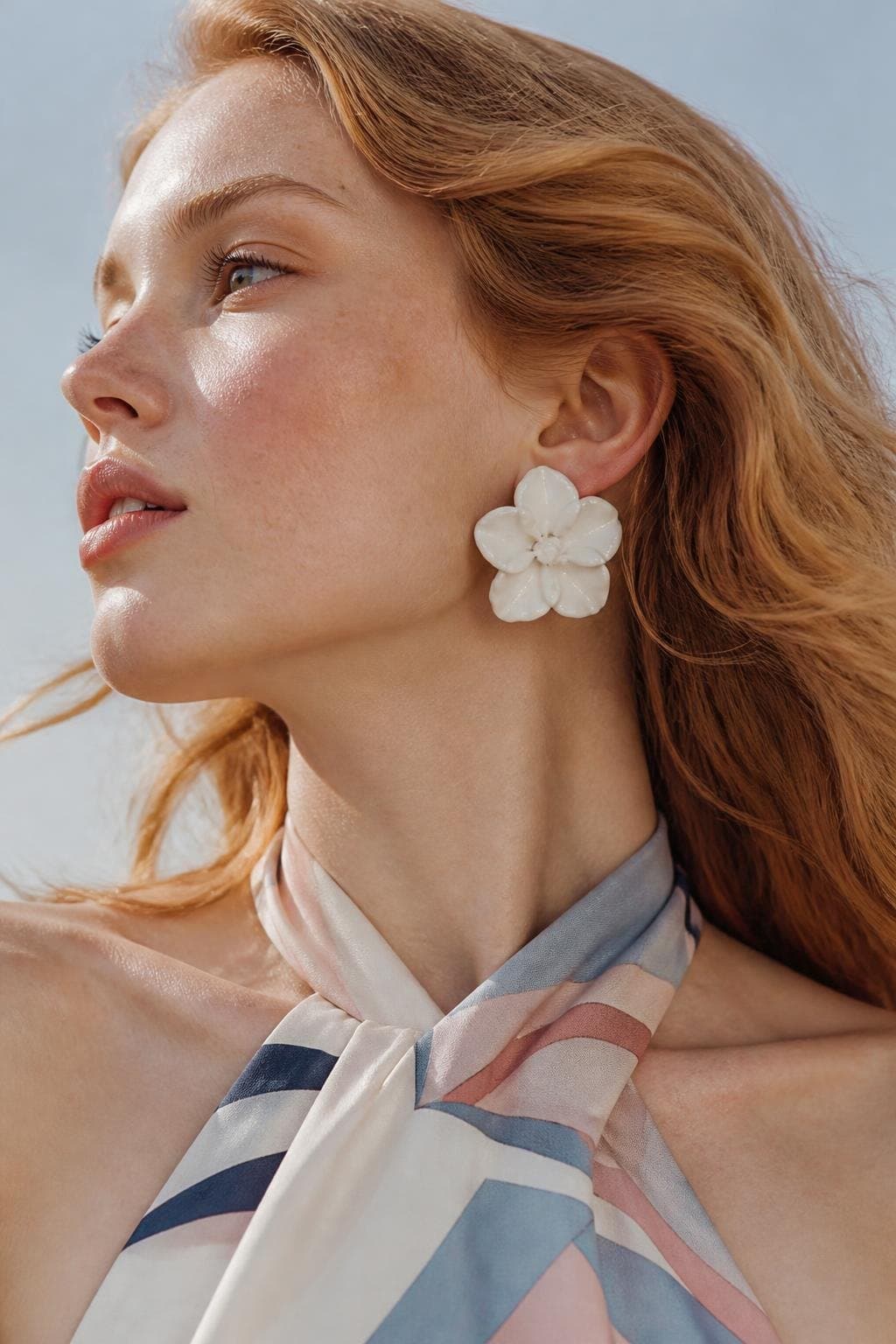 A model wearing a white flower earring and a pastel silk halter top